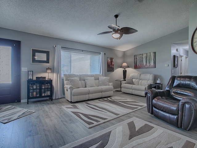 living room featuring a textured ceiling, vaulted ceiling, light hardwood / wood-style floors, and ceiling fan