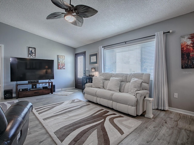 living room featuring ceiling fan, lofted ceiling, a textured ceiling, and light hardwood / wood-style flooring