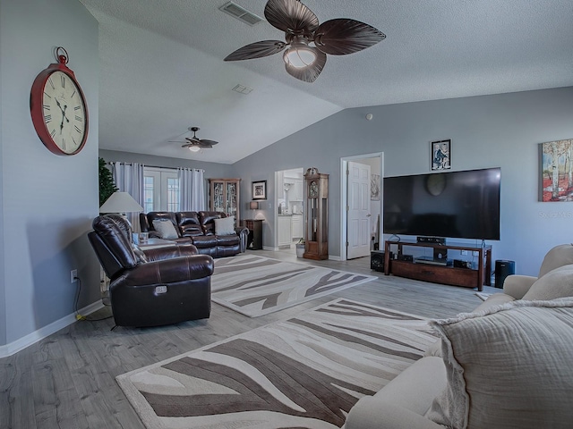 living room featuring vaulted ceiling, ceiling fan, a textured ceiling, and light wood-type flooring