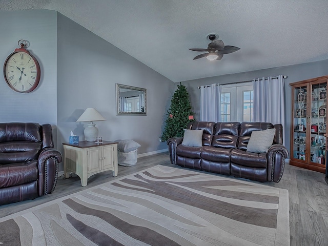 living room featuring french doors, vaulted ceiling, a textured ceiling, light wood-type flooring, and ceiling fan