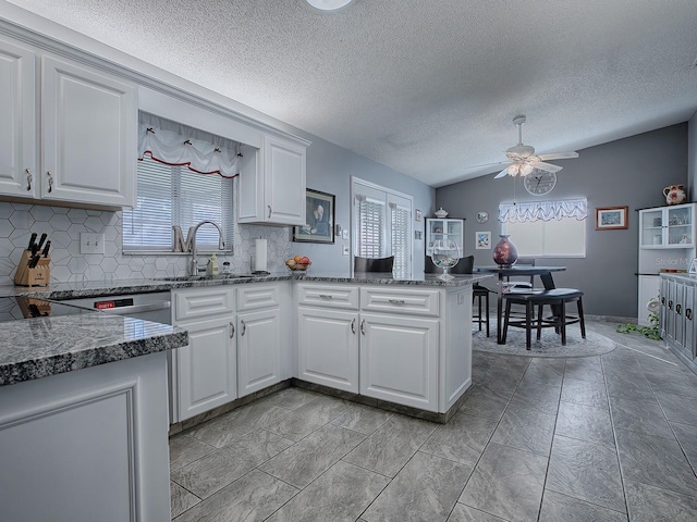 kitchen featuring white cabinetry, lofted ceiling, kitchen peninsula, and sink