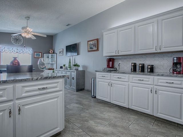 kitchen featuring white cabinetry, backsplash, a textured ceiling, and ceiling fan