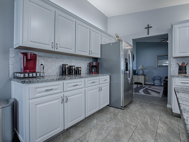 kitchen featuring stainless steel refrigerator with ice dispenser, white cabinets, and decorative backsplash