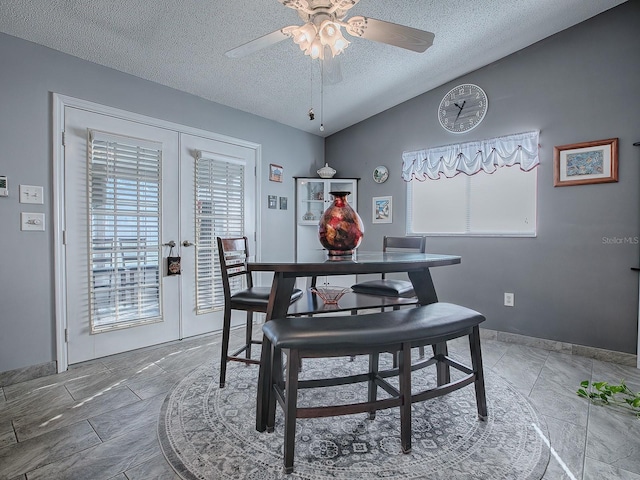 dining area featuring vaulted ceiling, ceiling fan, a textured ceiling, and french doors