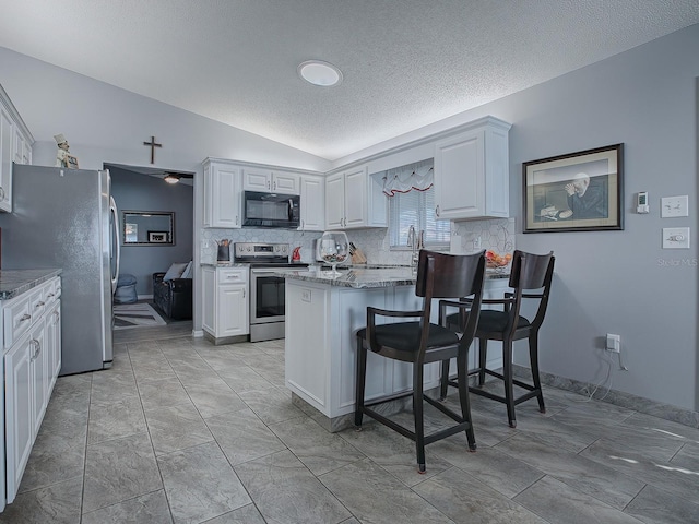 kitchen featuring lofted ceiling, kitchen peninsula, white cabinets, and appliances with stainless steel finishes