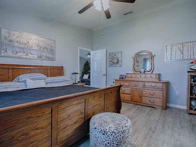 bedroom with a textured ceiling, ceiling fan, and light hardwood / wood-style floors