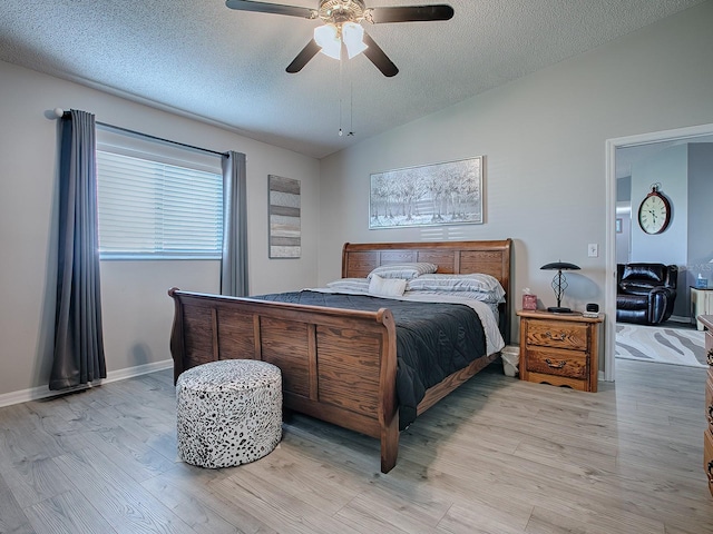 bedroom with a textured ceiling, vaulted ceiling, light hardwood / wood-style floors, and ceiling fan