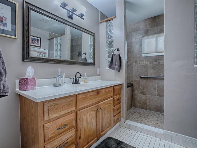 bathroom featuring vanity, tile patterned flooring, and a tile shower