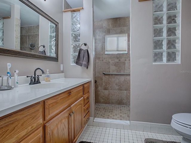 bathroom featuring vanity, tiled shower, tile patterned floors, and toilet