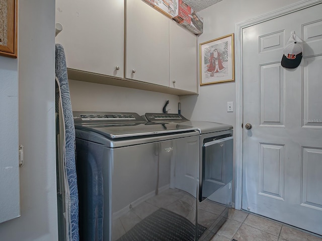 washroom featuring light tile patterned floors, washing machine and dryer, and cabinets