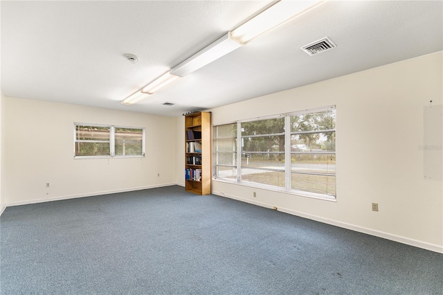 empty room with a wealth of natural light and dark carpet