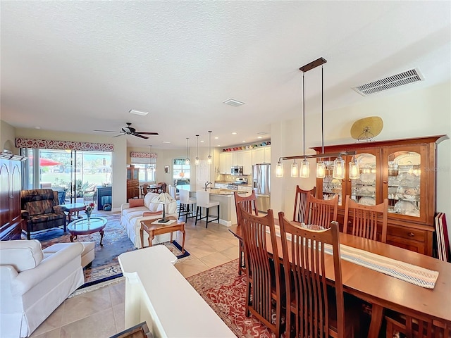 dining area featuring ceiling fan, light tile patterned flooring, and a textured ceiling