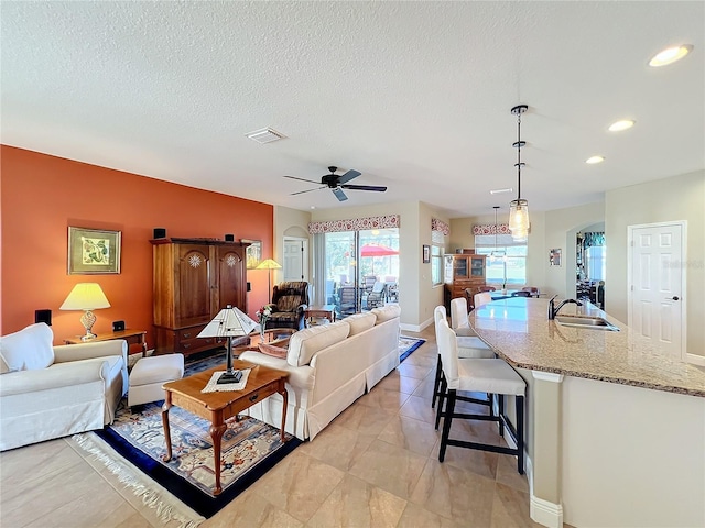 living room featuring ceiling fan, sink, and a textured ceiling