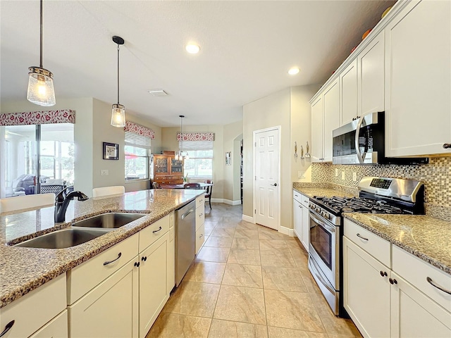 kitchen featuring pendant lighting, sink, light stone countertops, and stainless steel appliances