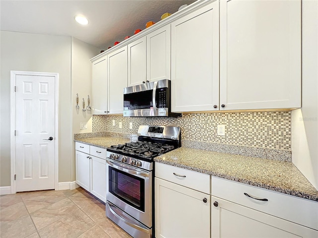 kitchen featuring light stone counters, white cabinets, stainless steel appliances, and light tile patterned floors