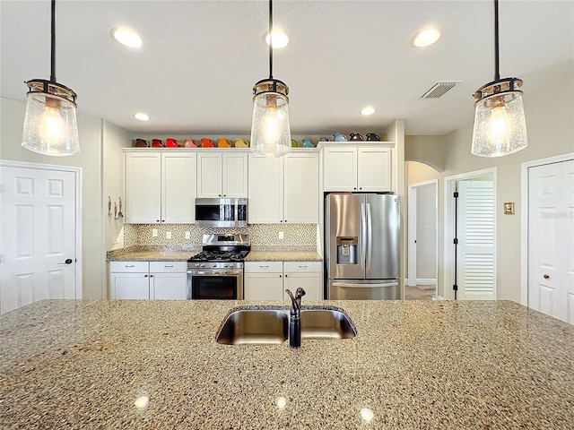 kitchen featuring pendant lighting, white cabinets, and stainless steel appliances