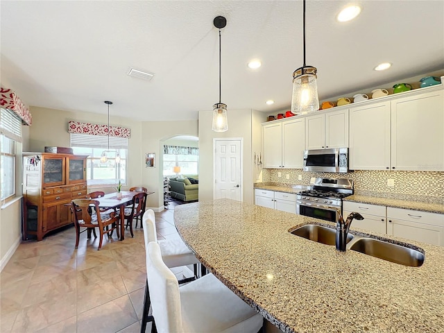 kitchen with white cabinets, hanging light fixtures, sink, and appliances with stainless steel finishes