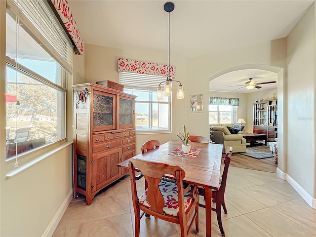 dining room with light tile patterned floors and ceiling fan with notable chandelier