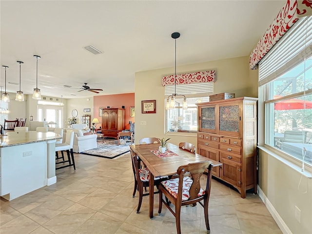 tiled dining area featuring ceiling fan with notable chandelier and a wealth of natural light