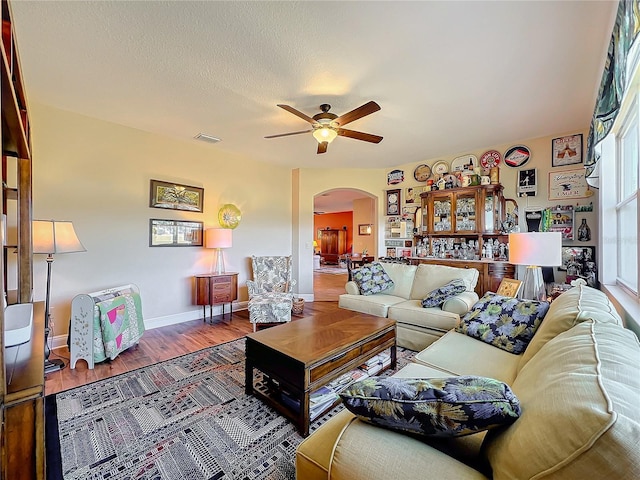 living room featuring ceiling fan, wood-type flooring, and a textured ceiling