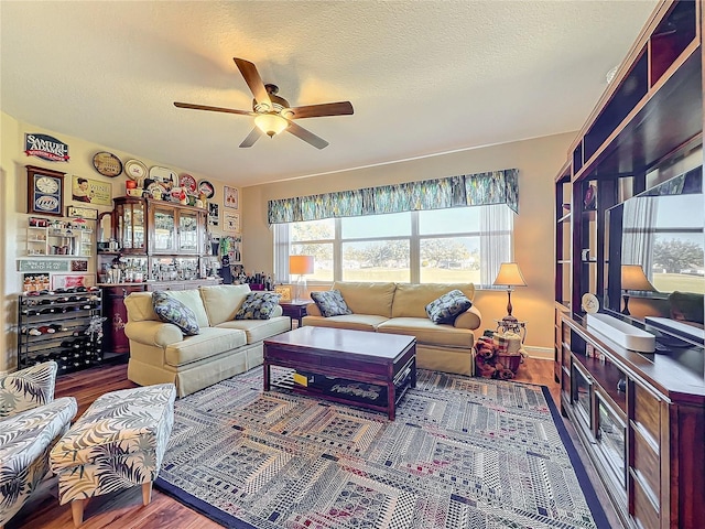 living room with a textured ceiling, ceiling fan, and dark wood-type flooring