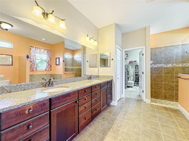 bathroom with tile patterned flooring, a tile shower, and vanity