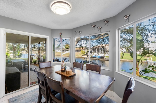 tiled dining area featuring a water view and a textured ceiling