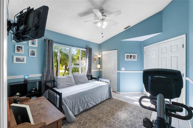 tiled bedroom featuring a textured ceiling, ceiling fan, and lofted ceiling