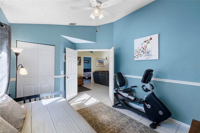 tiled bedroom with a textured ceiling, ceiling fan, a closet, and vaulted ceiling