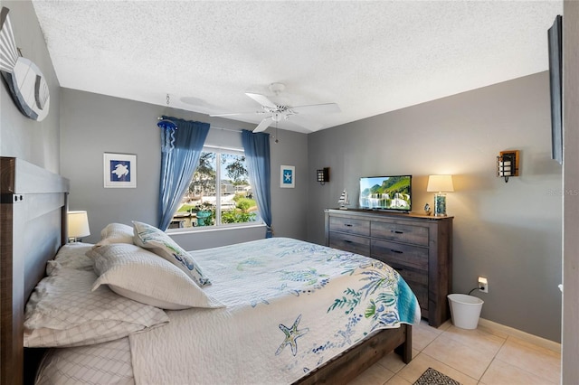 bedroom featuring ceiling fan, light tile patterned floors, and a textured ceiling