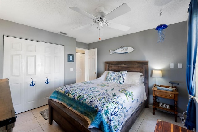 tiled bedroom with ceiling fan, a textured ceiling, and a closet