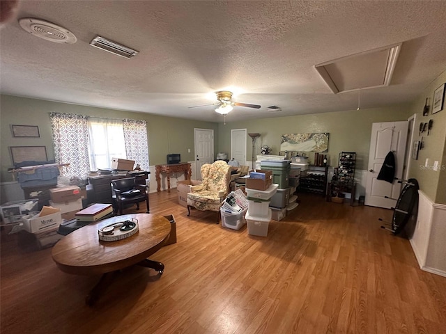 living room with ceiling fan, a textured ceiling, and hardwood / wood-style flooring