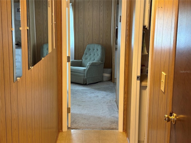 hall featuring light carpet and wood walls