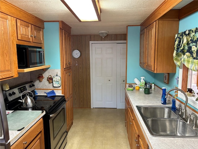 kitchen with stainless steel electric range oven, sink, and wooden walls