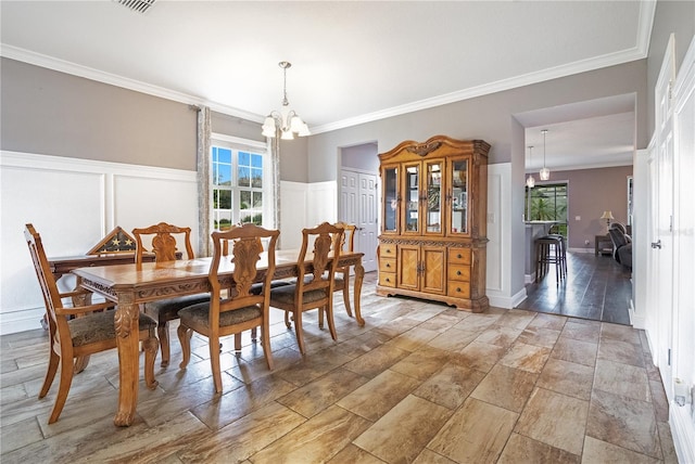 dining area with a healthy amount of sunlight, an inviting chandelier, and ornamental molding