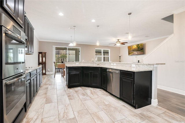 kitchen featuring a large island with sink, pendant lighting, light stone countertops, and stainless steel appliances