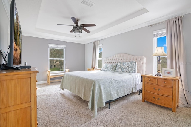 carpeted bedroom featuring ceiling fan and a raised ceiling