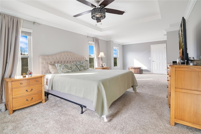 bedroom featuring light carpet, a tray ceiling, ceiling fan, and ornamental molding