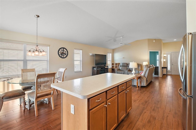 kitchen featuring hanging light fixtures, stainless steel fridge, lofted ceiling, a kitchen island, and ceiling fan with notable chandelier