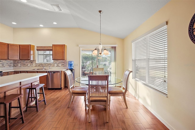 dining room with sink, an inviting chandelier, a textured ceiling, vaulted ceiling, and light wood-type flooring