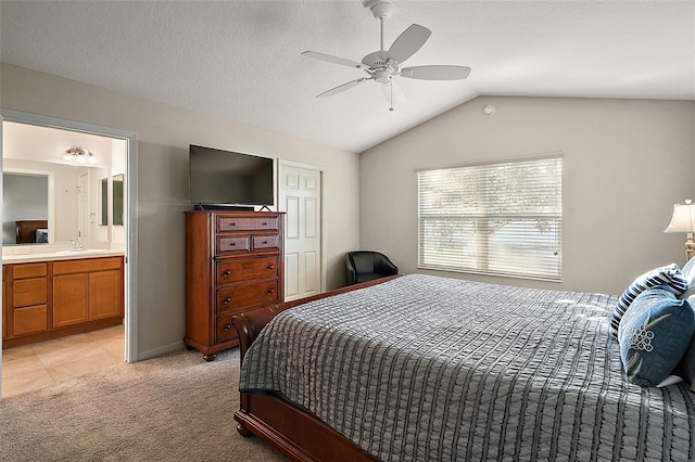 bedroom with ensuite bath, ceiling fan, sink, light colored carpet, and lofted ceiling