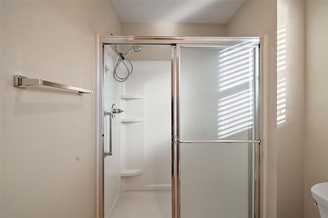 bathroom with a shower with shower door and toilet