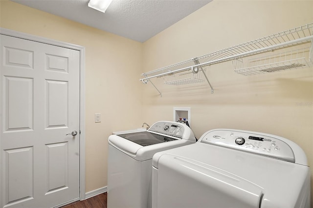 laundry room with dark hardwood / wood-style flooring, a textured ceiling, and washing machine and clothes dryer