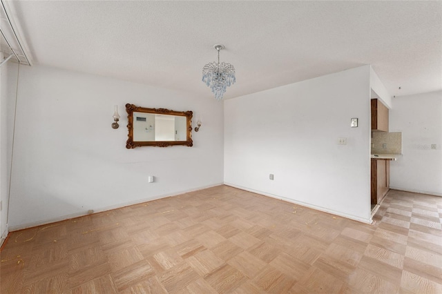 spare room featuring light parquet flooring, a chandelier, and a textured ceiling