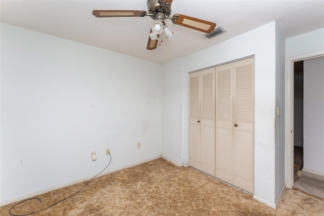 unfurnished bedroom featuring ceiling fan, a closet, light colored carpet, and a textured ceiling