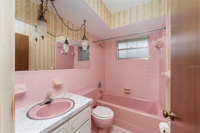 full bathroom with toilet, vanity, tile walls, and tiled shower / bath