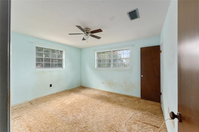 empty room with carpet flooring, ceiling fan, and a textured ceiling