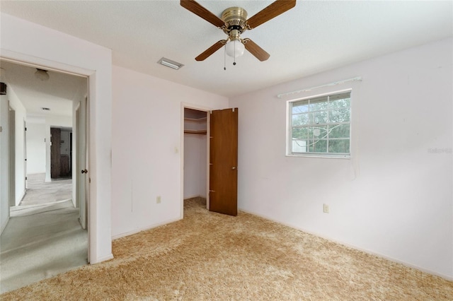 unfurnished bedroom featuring a closet, light colored carpet, and ceiling fan