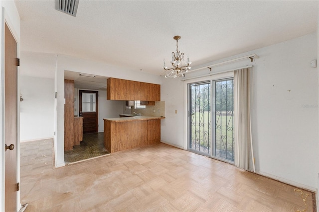 kitchen featuring light parquet floors, decorative backsplash, decorative light fixtures, kitchen peninsula, and a chandelier