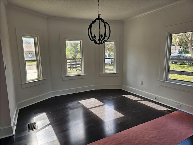 unfurnished dining area featuring a notable chandelier, crown molding, a textured ceiling, and dark wood-type flooring